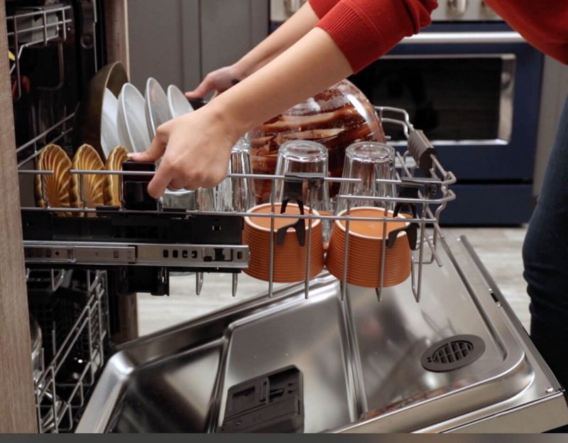 Woman adjusting loaded middle rack of dishwasher
