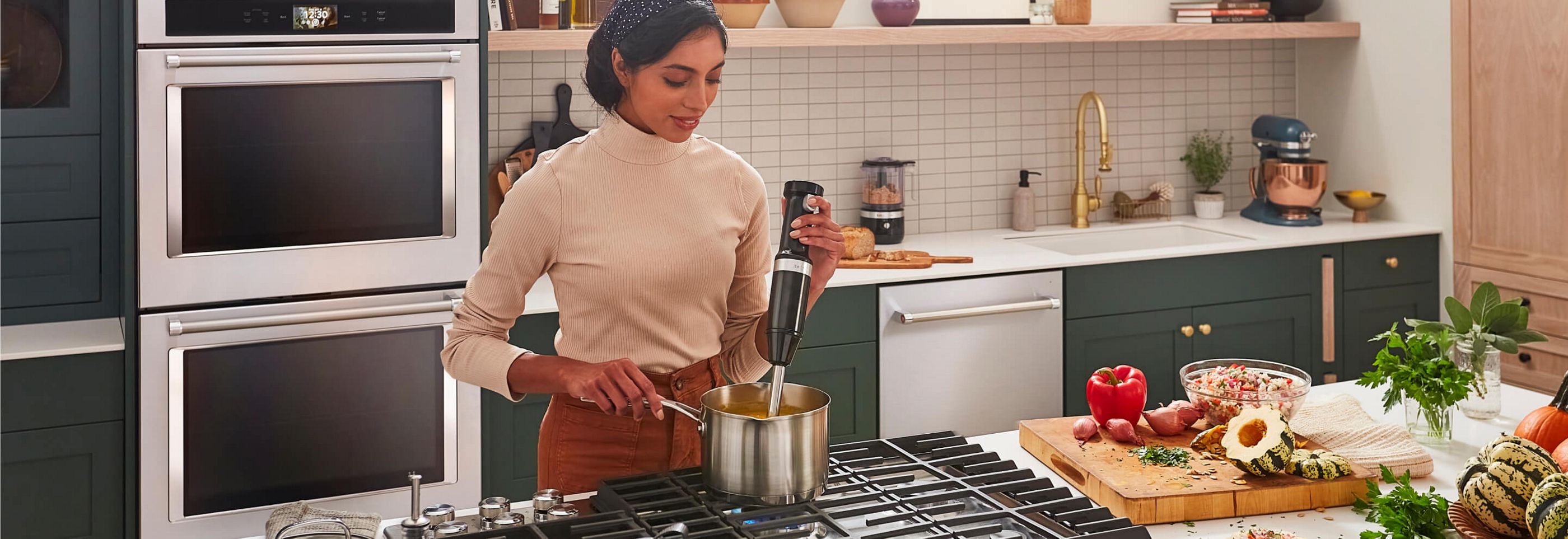 A person cooking in a kitchen full of KitchenAid® appliances.