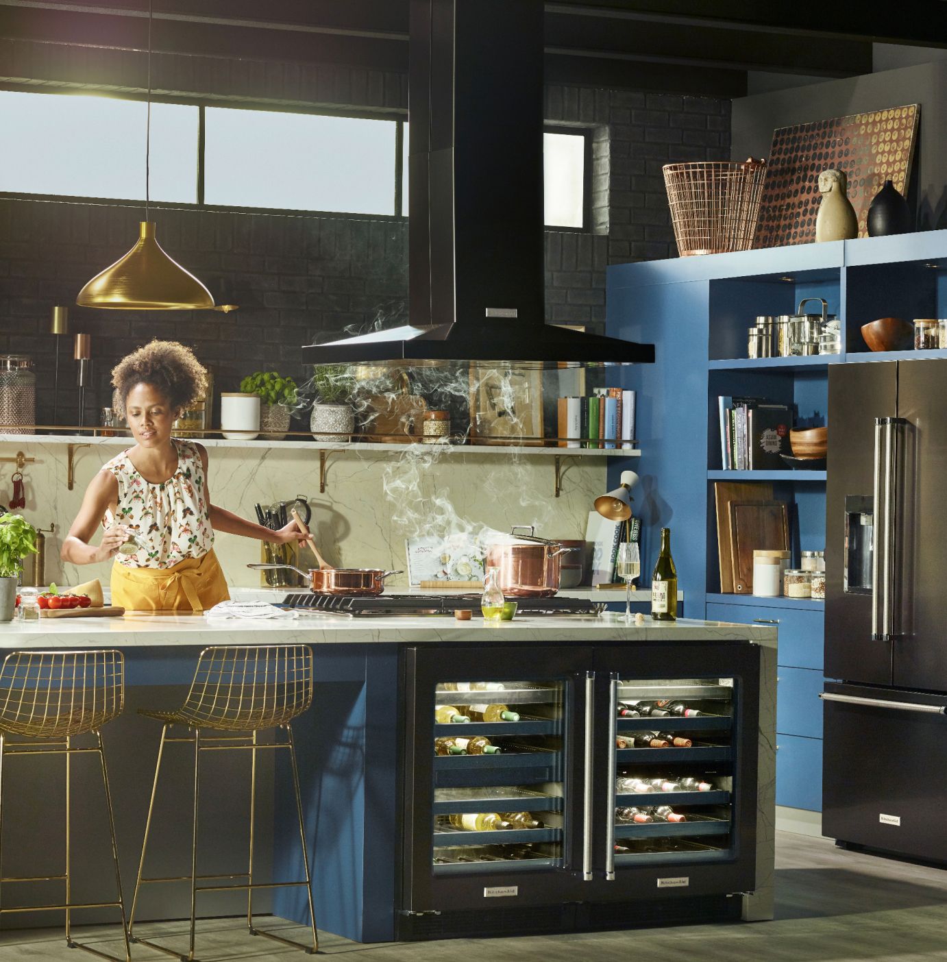 A woman cooking in a kitchen, featuring KitchenAid® undercounter refrigeration, ventilation and refrigeration.