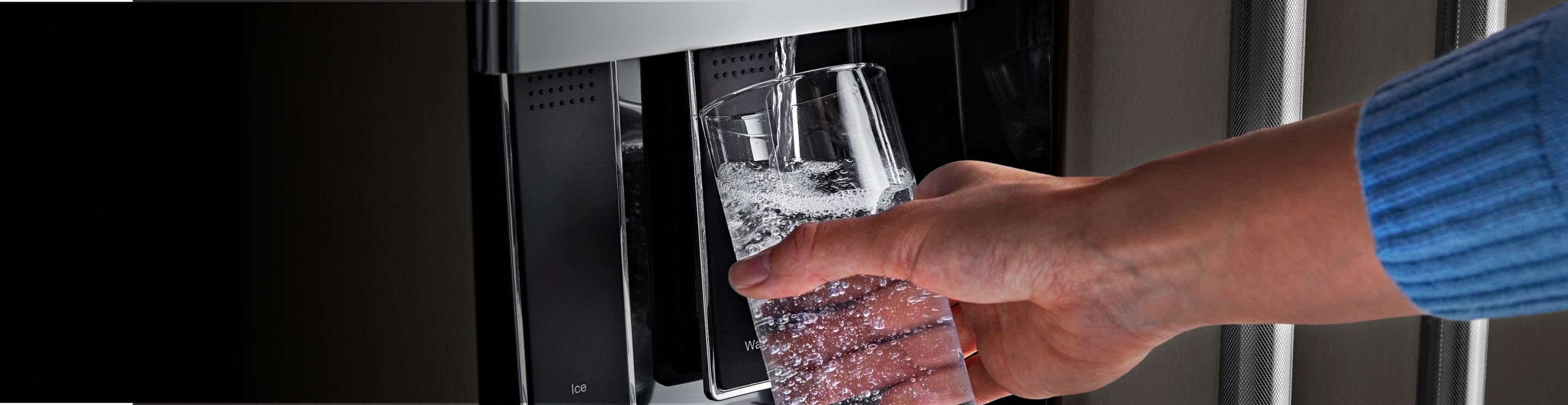 Filling a glass from a KitchenAid® refrigerator water dispenser.