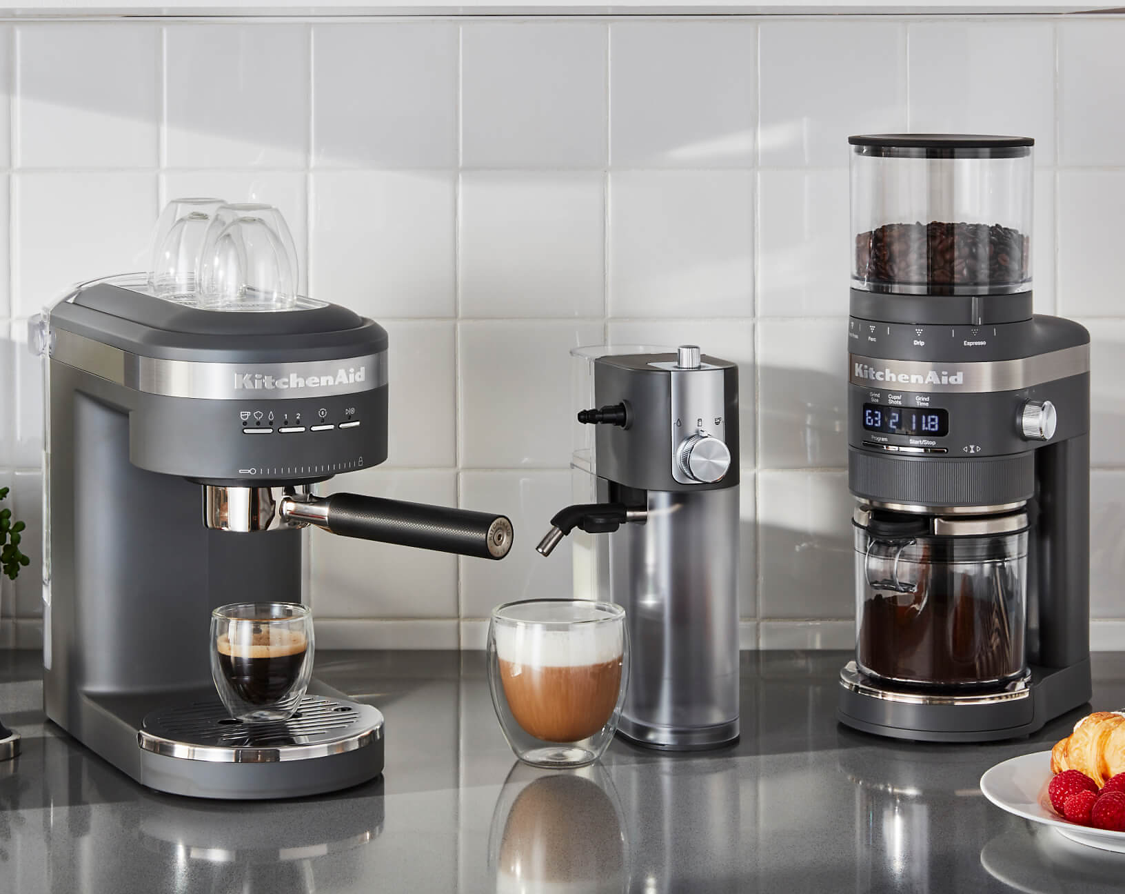 A KitchenAid® semi-automatic espresso machine, automatic milk frother attachment and burr grinder near prepared espresso.